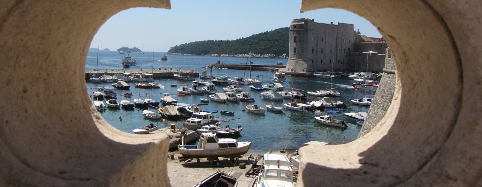 The view through the hole in the city wall onto the old city harbour and St. John fortress.